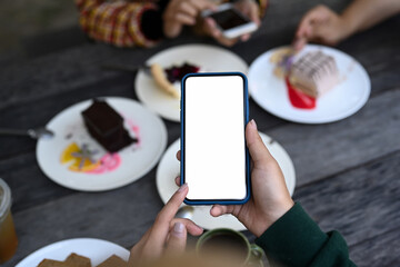 Close up view of young woman using smart phone taking photo of sweet dessert.