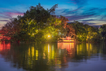 Fototapeta premium Hanoi Red Bridge at night. The wooden red-painted bridge over the Hoan Kiem Lake connects the shore and the Jade Island on which Ngoc Son Temple stands