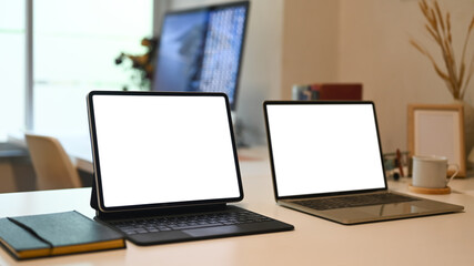 Mock up laptop and tablet computer on white office desk.  White display for web design promotion.