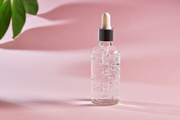 Anti aging serum in a glass bottle on a pink background.  Facial liquid serum with collagen and...