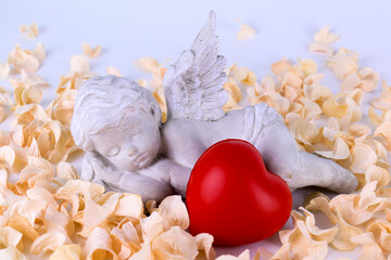 a sleeping angel and red heart bedded with soft petals 