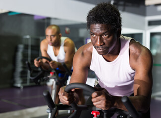 Fototapeta na wymiar Young adult man doing cardio workout cycling bike at fitness center
