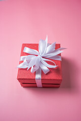 Red gift box with white bow on pink background top view, Valentines day, Flat lay style with copy space.