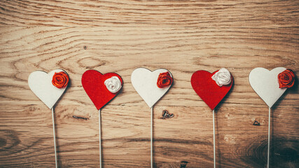 row of red and white hearts with sticks on wooden background