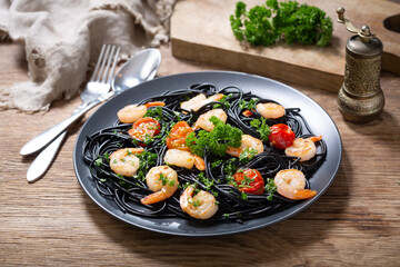plate of black pasta with shrimps and vegetables