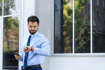 Handsome businessman looking at watch outdoors