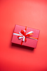 Red gift box with white and red bow on red background top view, Valentines day, Flat lay style with copy space.
