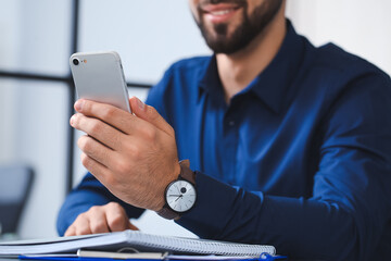 Handsome businessman with stylish wristwatch and mobile phone in office