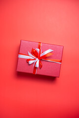 Red gift box with white and red bow on red background top view, Valentines day, Flat lay style with copy space.