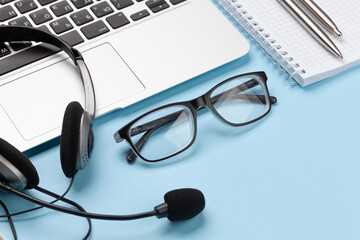 Office desk with headset, glasses and laptop