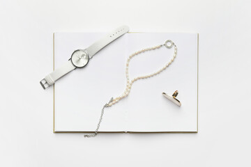 Stylish wristwatch and jewelry on white background