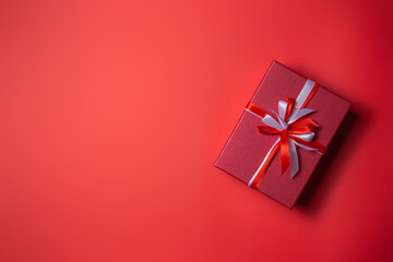Red gift box with white and red bow on red background top view, Valentines day, Flat lay style with copy space.