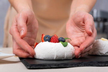 Obraz na płótnie Canvas Pastry chef prepares delicate cake with fresh berries. Cake Anna Pavlova. Close up.