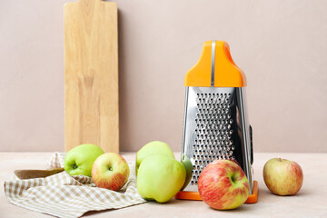 Metal grater and apples on table
