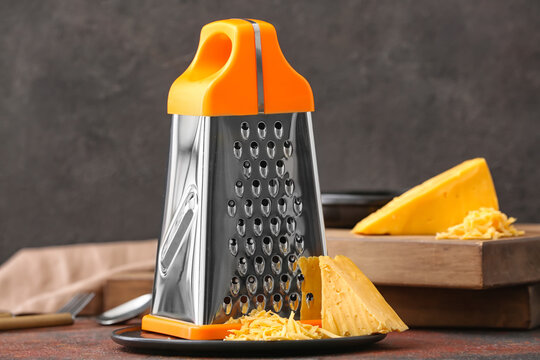 Metal grater and cheese on dark background