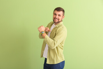 Handsome man with wristwatch on color background
