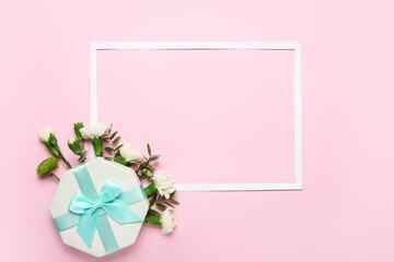 Frame with beautiful flowers and gift on color background