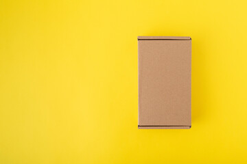 Cardboard box on yellow background top view. Craft packaging. Copy space. Mock up