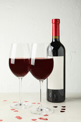 Bottle and glasses of red wine on white textured table