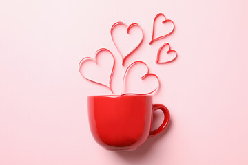 Red cup and decorative hearts on pink background