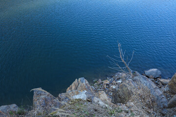 Stone rocks near water, on the background of lake, river, sea, ocean. Blue clear water. Artificial reservoirs