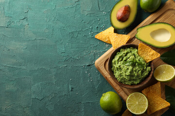 Concept of tasty eating with bowl of guacamole on green textured background - obrazy, fototapety, plakaty
