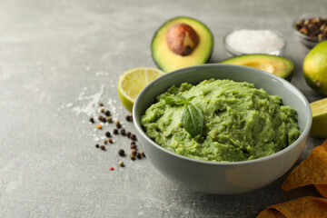 Concept of tasty eating with guacamole and ingredients on gray background