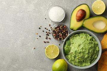 Concept of tasty eating with guacamole and ingredients on gray background