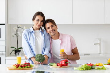 Happy couple is preparing vegan food on light kitchen.