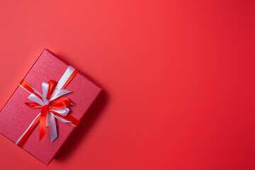 Red gift box with white and red bow on red background top view, Valentines day, Flat lay style with copy space.