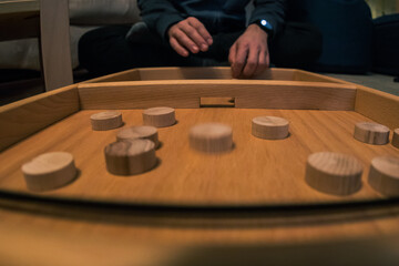 Obraz premium Wooden bard game where you shoot round wooden blocks through opening with help of an elastic band. Two players visible.
