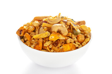 Pile of Indian spicy snacks (Namkeen) - 'All in one' in a white bowl, made with fried peanut, corn flakes, sweet pea, pulses, cashew nuts, etc. side view, against the white background.