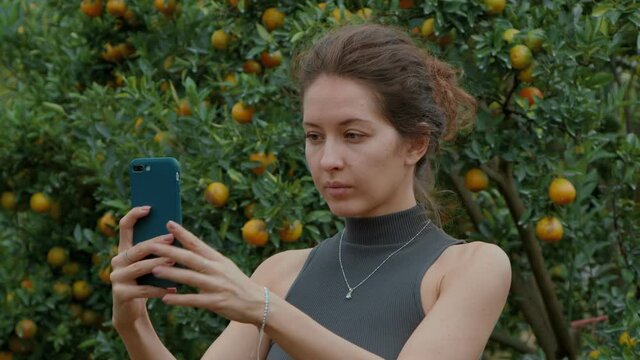 woman taking selfie picture in an orange orchard. cinematic shot bmpcc 6k