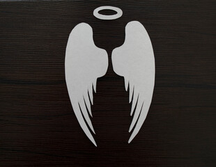 nimbus and angel wings made of white paper on a dark wooden background