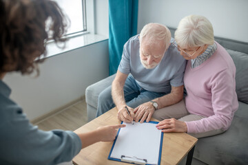 Senior couple having an appointment with health insurance agent and signing the contract