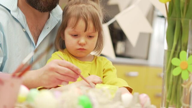 Happy easter. A dad and daughter painting Easter eggs at domestic kitchen