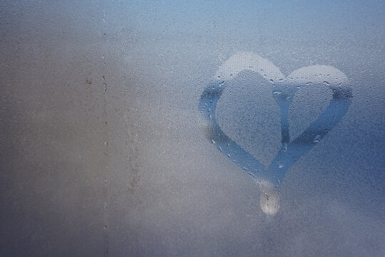 love heart on cold fogged window background, closeup image. a window with water drops photo
