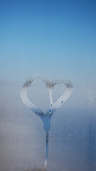 Naklejka na ściany i meble love heart on cold fogged window background, closeup image. a window with water drops photo