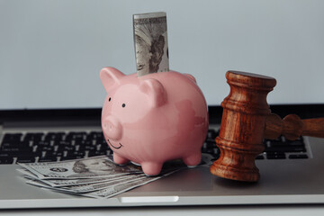 Judge wooden gavel and piggy bank on a keyboard close-up. Bank account arrest or online auction...