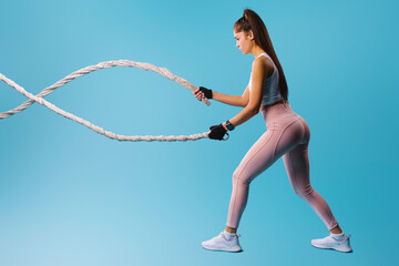 Sports girl with ropes in sportswear on a blue background. Sport and healthy lifestyle concept.