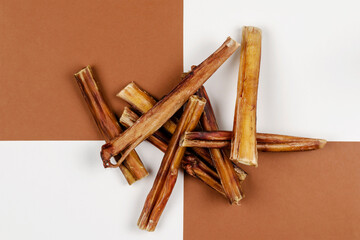 Dried bovine penis, bully sticks, beef pizzle for dogs on a brown and white background.