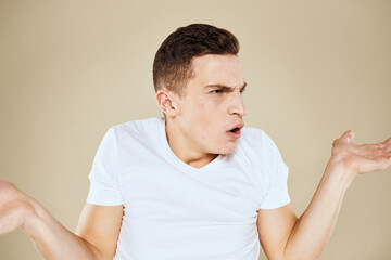 Emotional man facial expression gesture with hands white t-shirt beige background