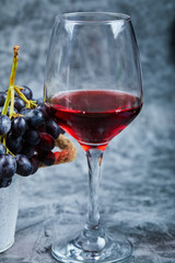 A glass of red wine on a marble background with grapes