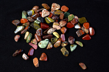 Naklejka premium Red and multicolored jasper polished tumblestones on black background