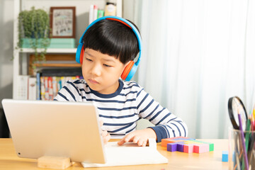 Portrait of smart Asian student boy with headphone, take note, study at home with tablet computer in online classroom during Covid-19 pandemic lockdown. New normal in technology, education, homeschool