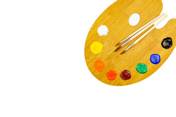 Wooden palette with colored paints and brushes isolated on white background