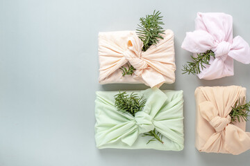 Fabric wrapped gifts with green branches, reusable sustainable gift wrapping alternative zero waste concept.top view.