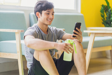 Asian man resting and using phone after exercising