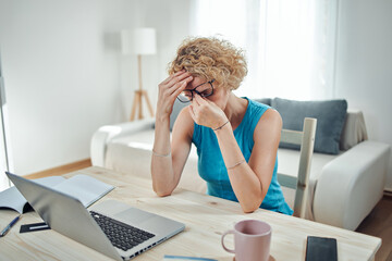Woman working from home and being depressed, tired with headache. Modern concept and problems with freelancers.