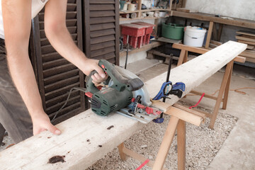 Male carpenter working with wood material in a garage.